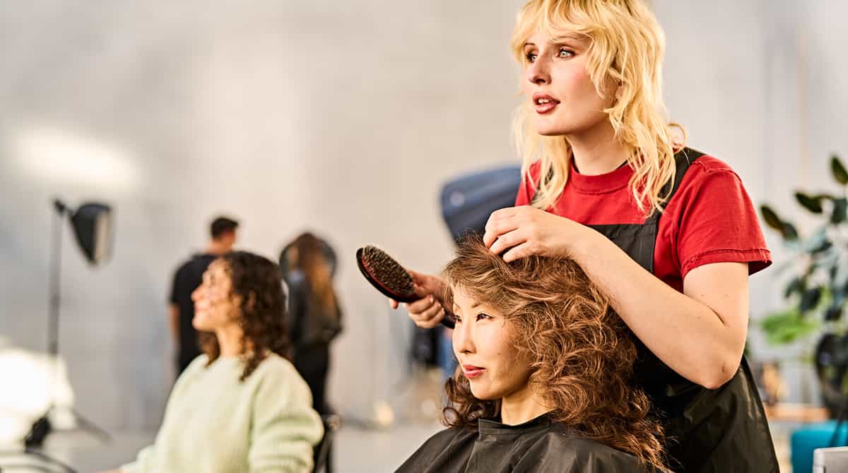 Hairdresser showing client's amazing finished hairstyle after using Wella products